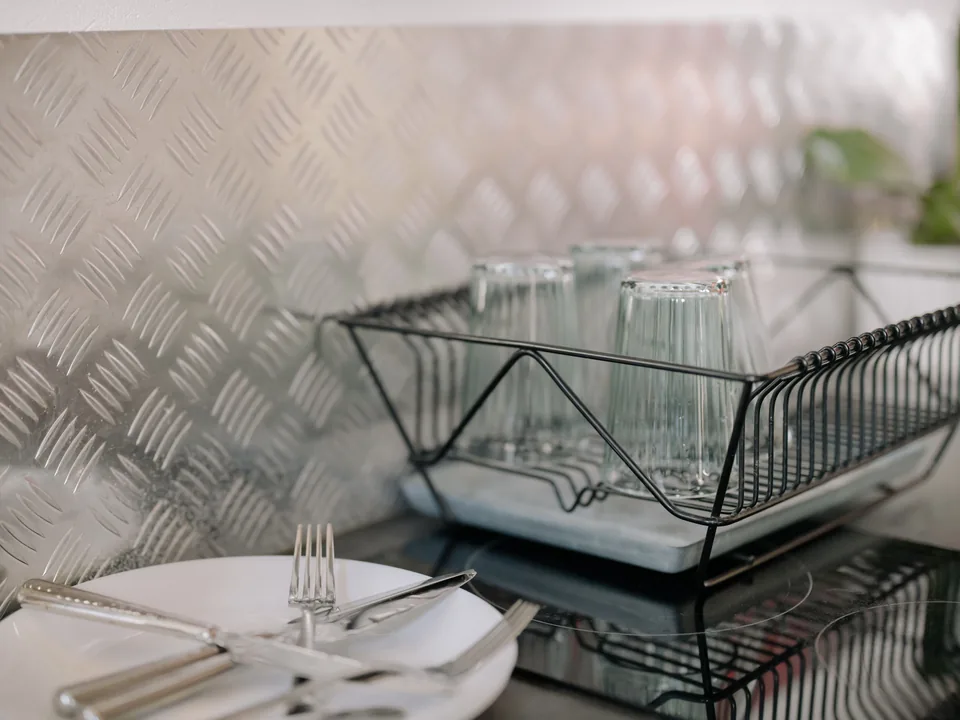 Black wire dish rack holding clear glasses beside a kitchen sink.